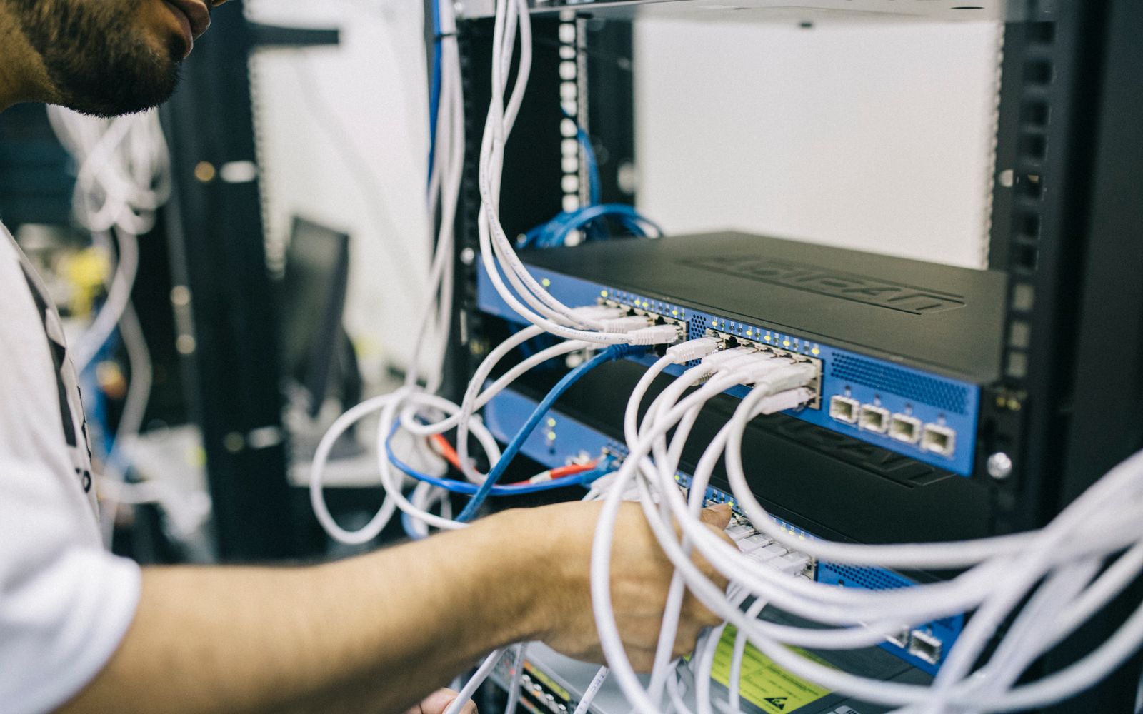 Engineer terminating structured cabling in a network rack